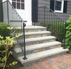 a set of stairs leading up to a house with black iron railing and handrails