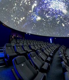 an auditorium with rows of seats in front of a large screen and stars on the ceiling