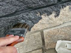 a person is holding a brush near a brick wall that has been gutted with cement