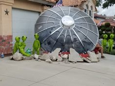 some people are sitting in front of a large object on the sidewalk with other statues around it