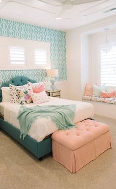 a bedroom with blue and white wallpaper, pink ottomans, and a large bed