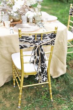 the table is set up with gold chairs and black and white napkins on it