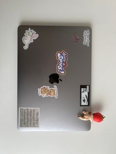 a laptop computer with stickers on the cover and an apple toy next to it