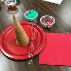 an ice cream cone sitting on top of a red paper plate next to other items