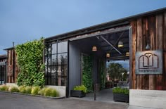 the entrance to a restaurant with wooden walls and plants growing on it's side