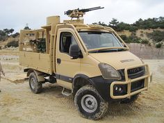 a man standing next to a white truck on top of a dirt field with a machine mounted on the back of it