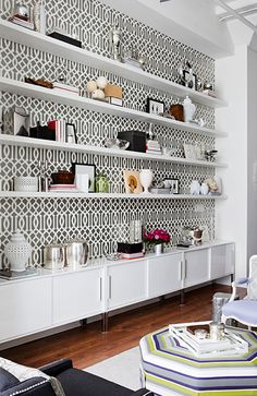 a living room filled with lots of furniture and shelves covered in wall coverings next to a window