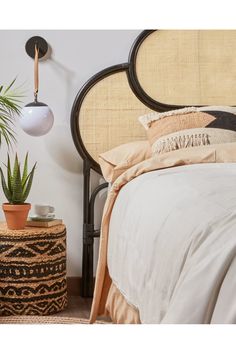 a bedroom with a bed, plant and two lamps