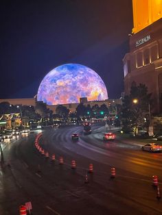 an image of a large ball in the sky over a city street at night time