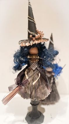 a doll with blue hair wearing a witches hat and holding a broom in her hand