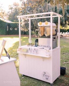 an outdoor ice cream cart in the middle of a lawn with trees and grass behind it