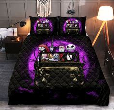 a bed covered in purple and black comforter with halloween decorations on it's head