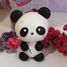 a panda bear figurine sitting next to some flowers