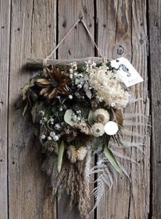 an arrangement of dried flowers hanging on a wooden wall with a price tag attached to it