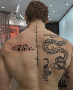 a man with a tattoo on his back and the words under your spell written in black ink