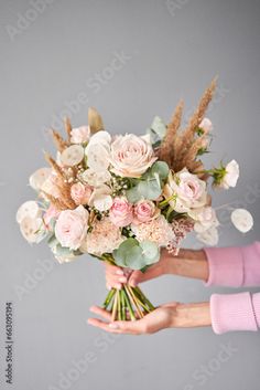 a woman holding a bouquet of flowers in her hands on a gray background with copy space