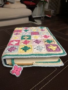 an open crocheted book sitting on top of a wooden table next to a couch