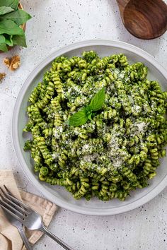 a white bowl filled with green pasta and pesto