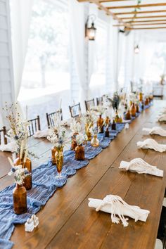 the table is set up for an event with blue runneres and vases filled with flowers