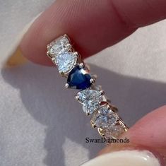 a woman's hand holding a blue and white ring with three diamonds on it