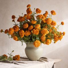 a white vase filled with orange flowers on top of a table