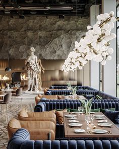 an elegant restaurant with blue velvet booths and marbled tables in front of a statue