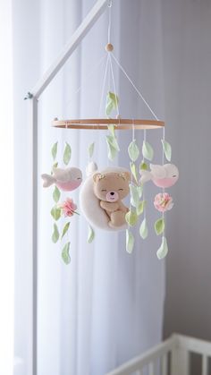 a baby crib with a teddy bear mobile hanging from it's side,