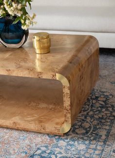 a coffee table with a vase on it and a rug in front of the table