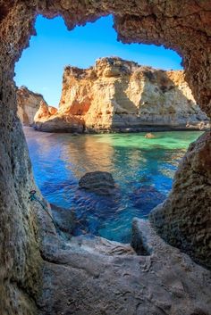 an ocean cave with blue water and cliffs in the background