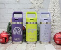 three different colored yeti bottles sitting next to each other in front of a christmas tree