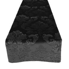 a black and silver table runner with floral designs on the top, in front of a white background