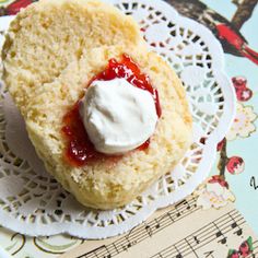 a piece of bread with cream on it sitting on top of a doily next to a sheet of music