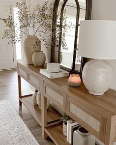 a table with a mirror, vases and lamp on it in a living room