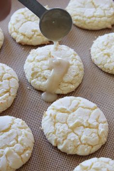 a cookie being drizzled with icing on a baking sheet and surrounded by other cookies