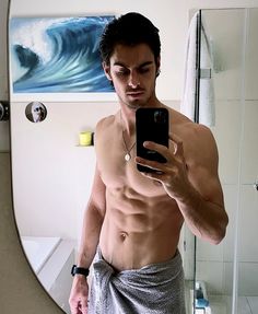 a shirtless man taking a selfie in front of a mirror with his cell phone