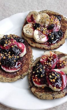 three pancakes with fruit toppings are on a white plate