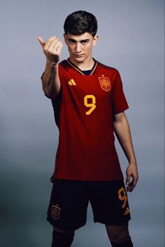 a young man is posing for a photo with his hand up in the air while wearing a soccer uniform