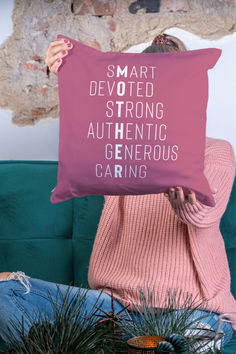 a woman sitting on a couch holding a pillow that says smart devoted strong authentic generous caring