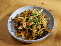 a white bowl filled with potato chips on top of a wooden table