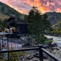 the sun is setting over a river with mountains in the background