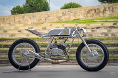 a silver motorcycle parked on the side of a road next to some steps and grass