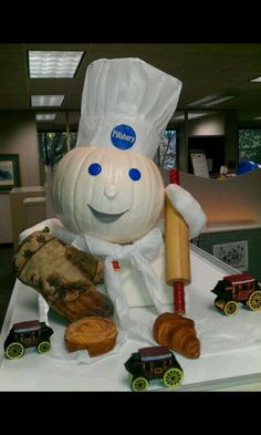 a sculpture of a chef holding a rolling doughnut on top of a white table