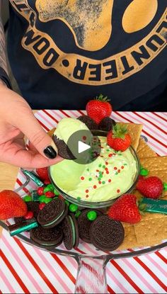 someone decorating a cake with strawberries and cookies