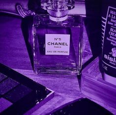 a bottle of chanel perfume sitting on top of a wooden table next to other items