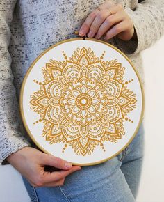 a woman holding a cross - stitch pattern in her hands