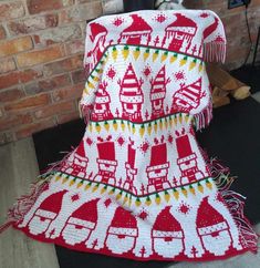 a red and white blanket sitting on top of a black floor next to a brick wall