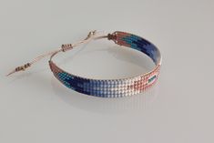 a close up of a bracelet on a white surface with blue, pink and silver beads