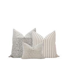 three pillows with different patterns on them, one in grey and the other in white