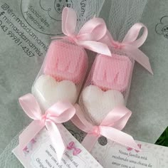 two pink and white baby booties with hearts on them sitting next to a tag