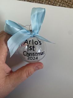 a hand holding an ornament that says arlo's 1st christmas 2012